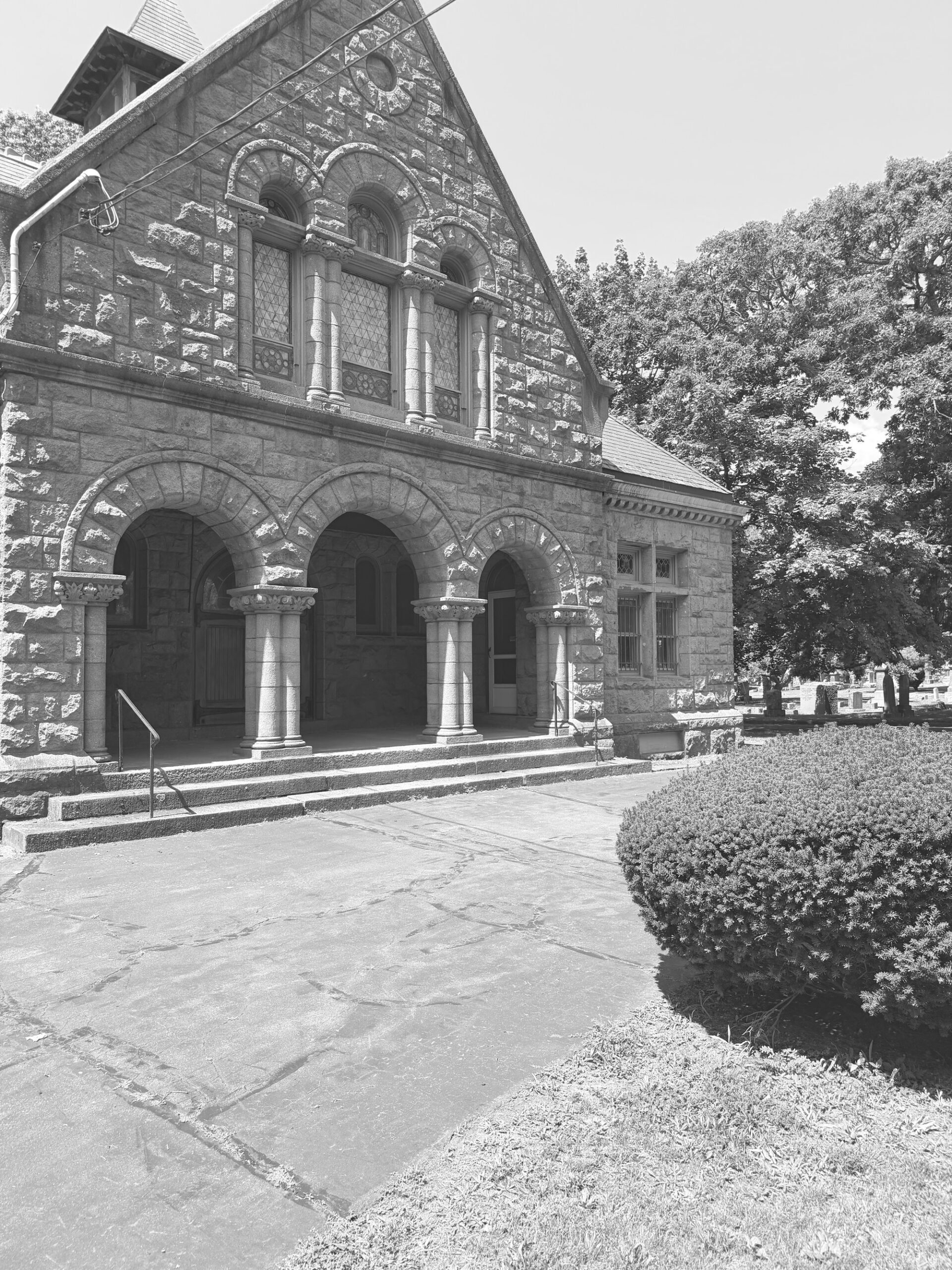 Stone memorial chapel at Evergreen Cemetery, New Haven, with arched porch and cemetery grounds beyond